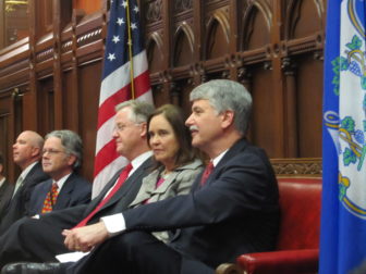 After a handshake, Sharkey and Williams take their seats, separated by Secretary of the State Denise Merrill.