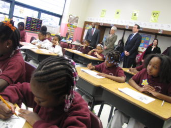 Jumoke Academy students work on an assignment while Gov. Dannel P. Malloy, Lt. Gov. Nancy Wyman and Michael Sharpe watch in the back.