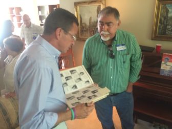 Malloy is shown his high school yearbook by Cris Casey, his opponent for president of the junior class in 1972.