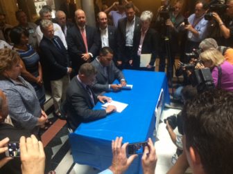 Kevin P. Brown, left, and Rodney A. Butler, tribal chairmen of the Mohegan and Mashantucket Pequote tribal nations, sign a joint venture deal to seek a third casino.