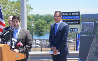 Traffic passes behind him on Route 9 as Gov. Dannel P. Malloy waits to be introduced by Mayor Dan Drew.