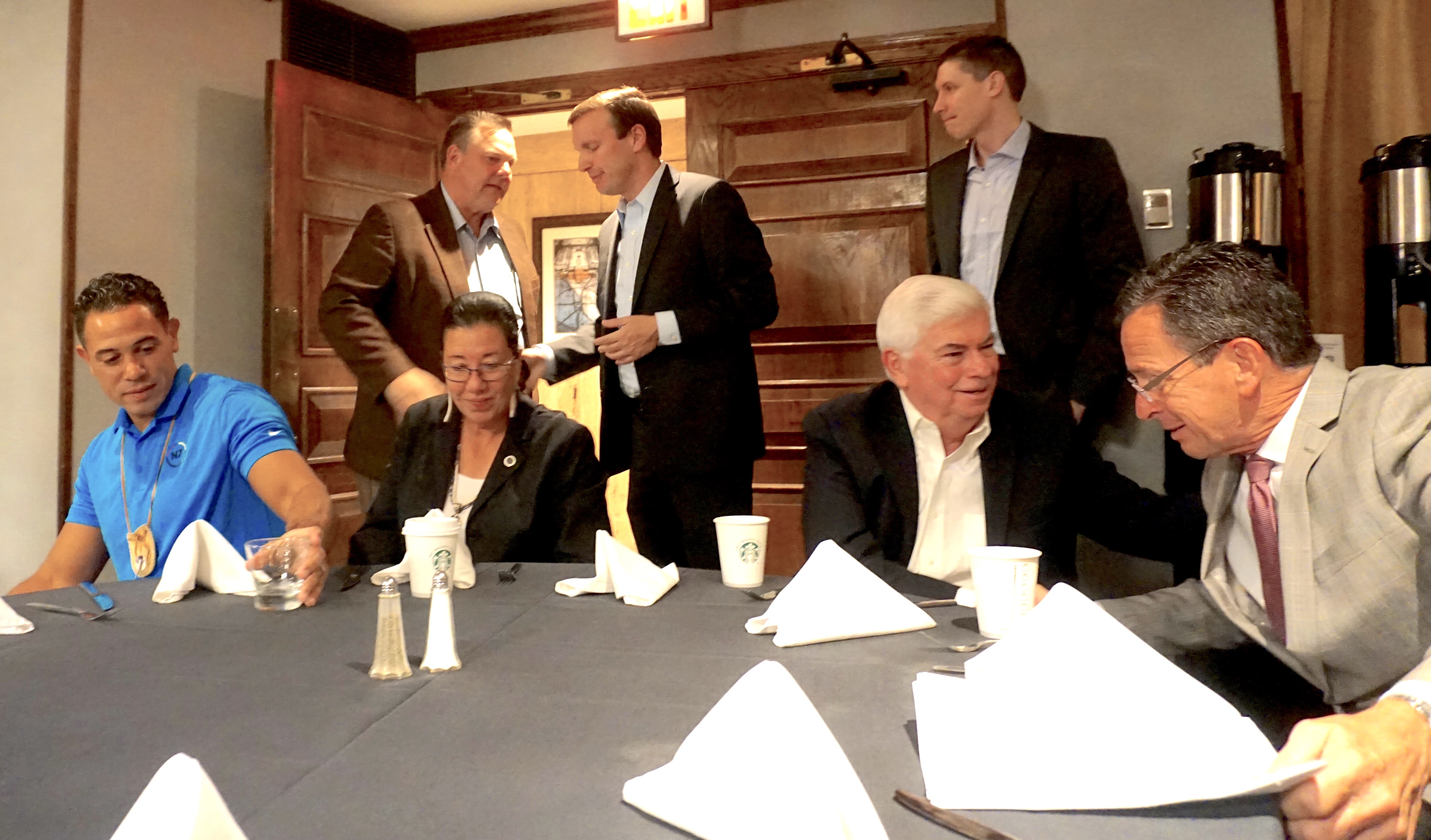 Tribal officials Rodney Butler and Kathy Regan-Pyne are seated with former senator Chris Dodd and Gov. Dannel P. Malloy. Standing at left are Sens. Jon Tester and Chris Murphy.