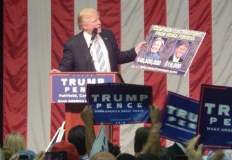At a rally in Fairfield, Donald J. Trump holds a sign showing how little he had gets from hedge fund managers compared to Clinton.