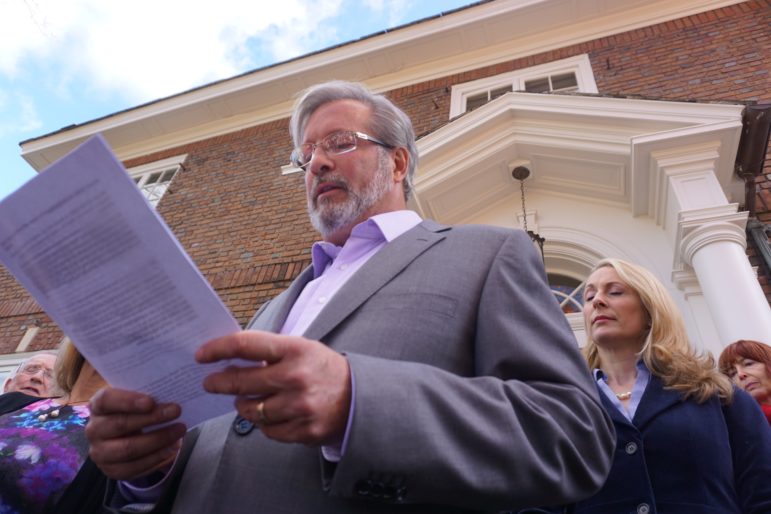 William Petit reading a statement accusing Labor United of libel. At right is his wife, Christine.