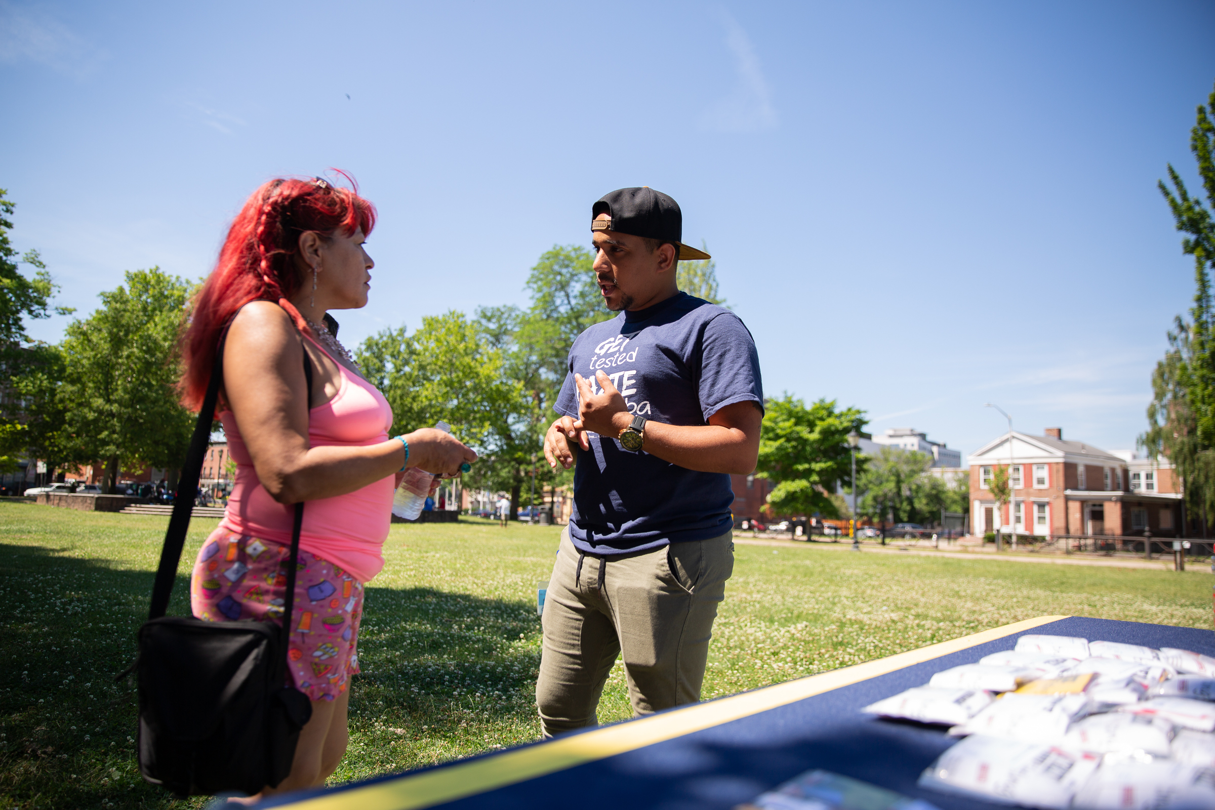 Community Renewal Team's Jovany Rolon speaks to Carmen Cruz about PrEP medication for HIV prevention in Hartford's Barnard Park. Photo by Ryan Caron King