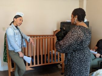 Brenda Whittingham, a social worker trainee with DCF, talks with Maguena Deslandes, a FAVOR staff member role-playing as a mom, in a simulated training exercise. Whitthingham was talking with Deslandes about safe sleeping practices for infants.