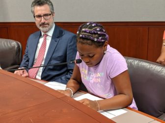 Jazzniqua Marrow, a ten-year old from Meriden, opened the 'town hall meeting' asking that adults make good decisions to help her get a good education. At left is former Meriden mayor, Manuel Santos.